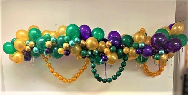 A mardi gras balloon garland arch purple, green and gold with balloon beads made with linking balloons